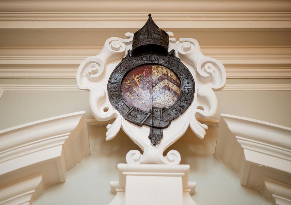 Ornate white crown molding and architectural details along a ceiling with decorative scrollwork patterns.