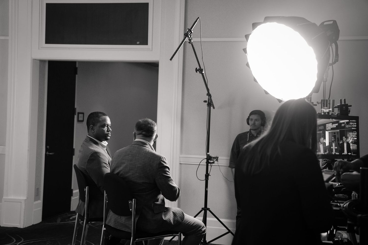 Behind the scenes black and white photo of a film production with lighting equipment and people on set.