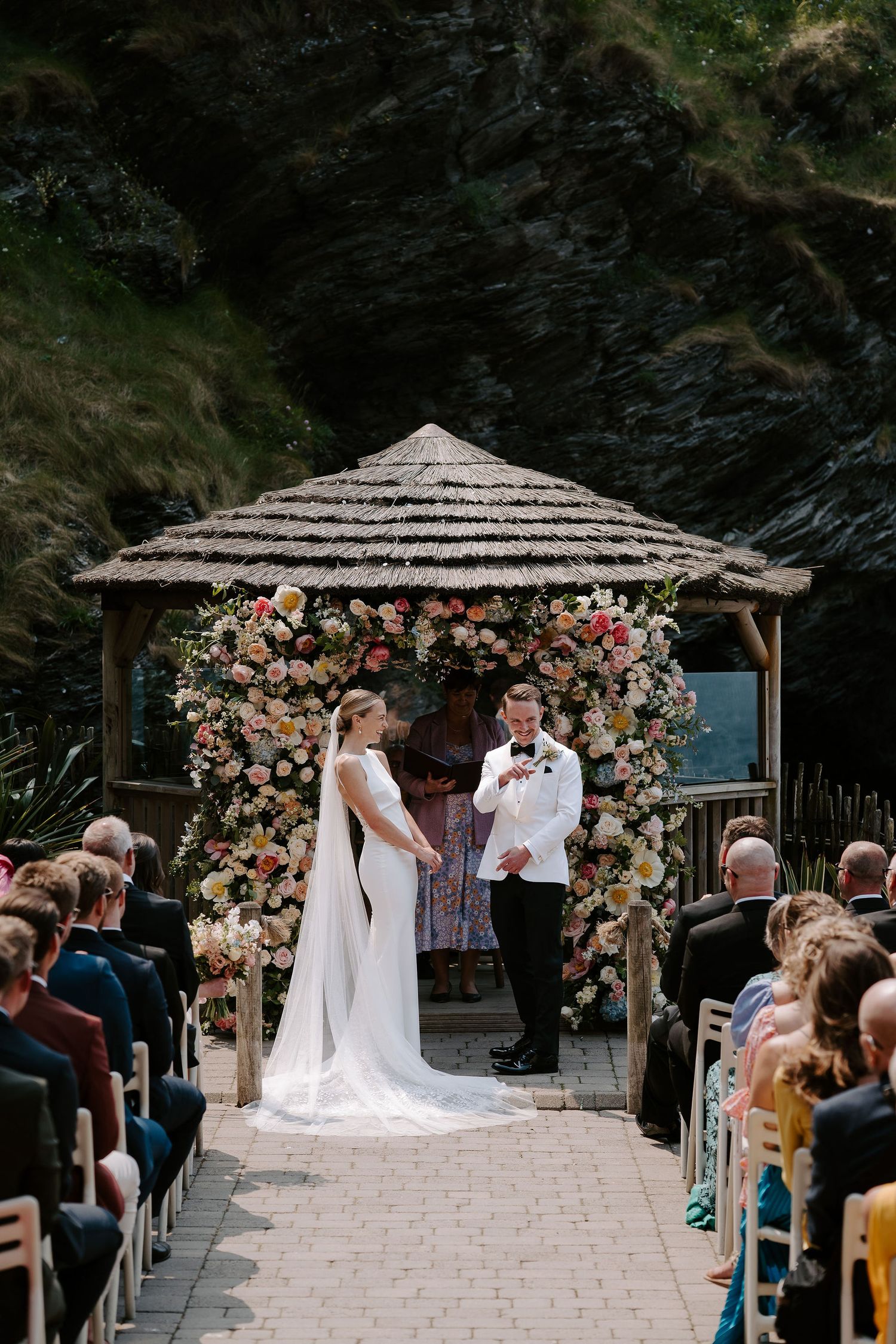Bride and Groom in front of floral arch next to the sea at Tunnels Beach Wedding Venue in North Devon