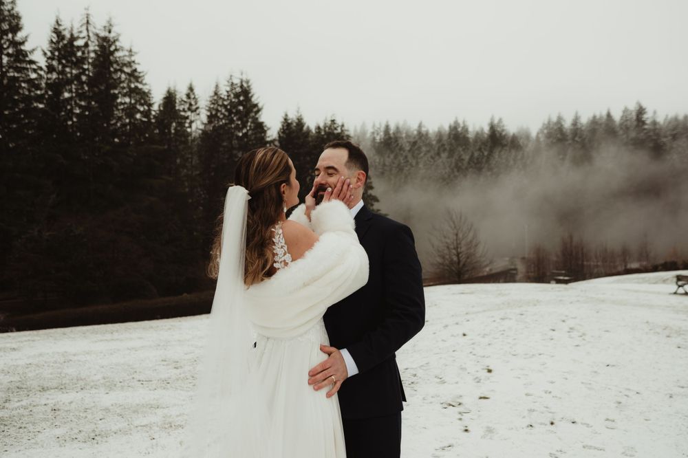 Candid wedding moment captured in a winter forest setting with misty atmosphere.