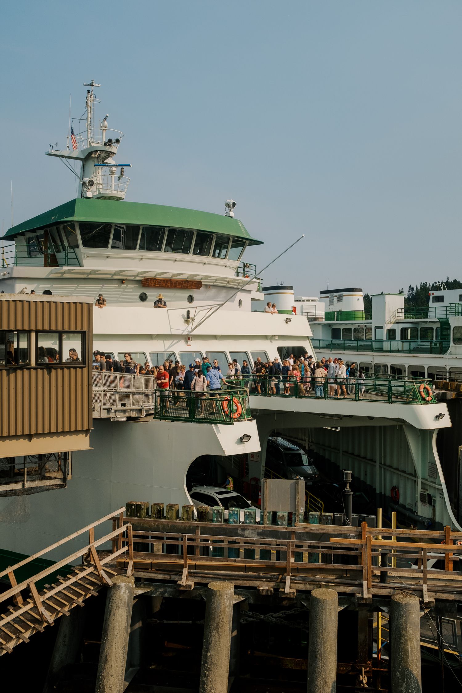 Washington State Ferry docked at terminal with passengers waiting on deck and walkways during sunny day.
