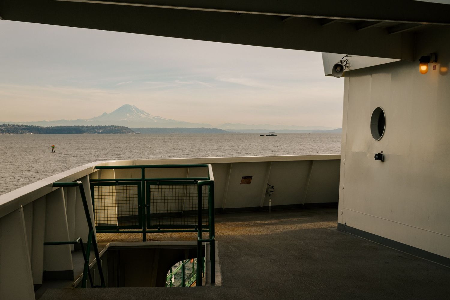 View from a Washington State ferry deck showing Mt. Rainier in the distance across Puget Sound at sunset.