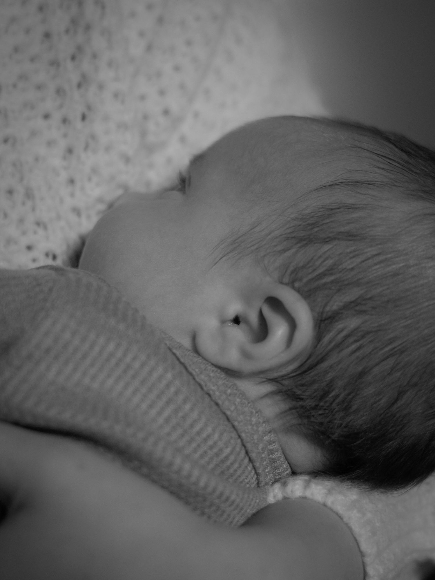 Black and white profile view of sleeping infant in knitted clothing.