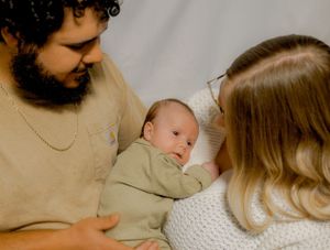 Family gathered together on couch for intimate portrait with newborn.