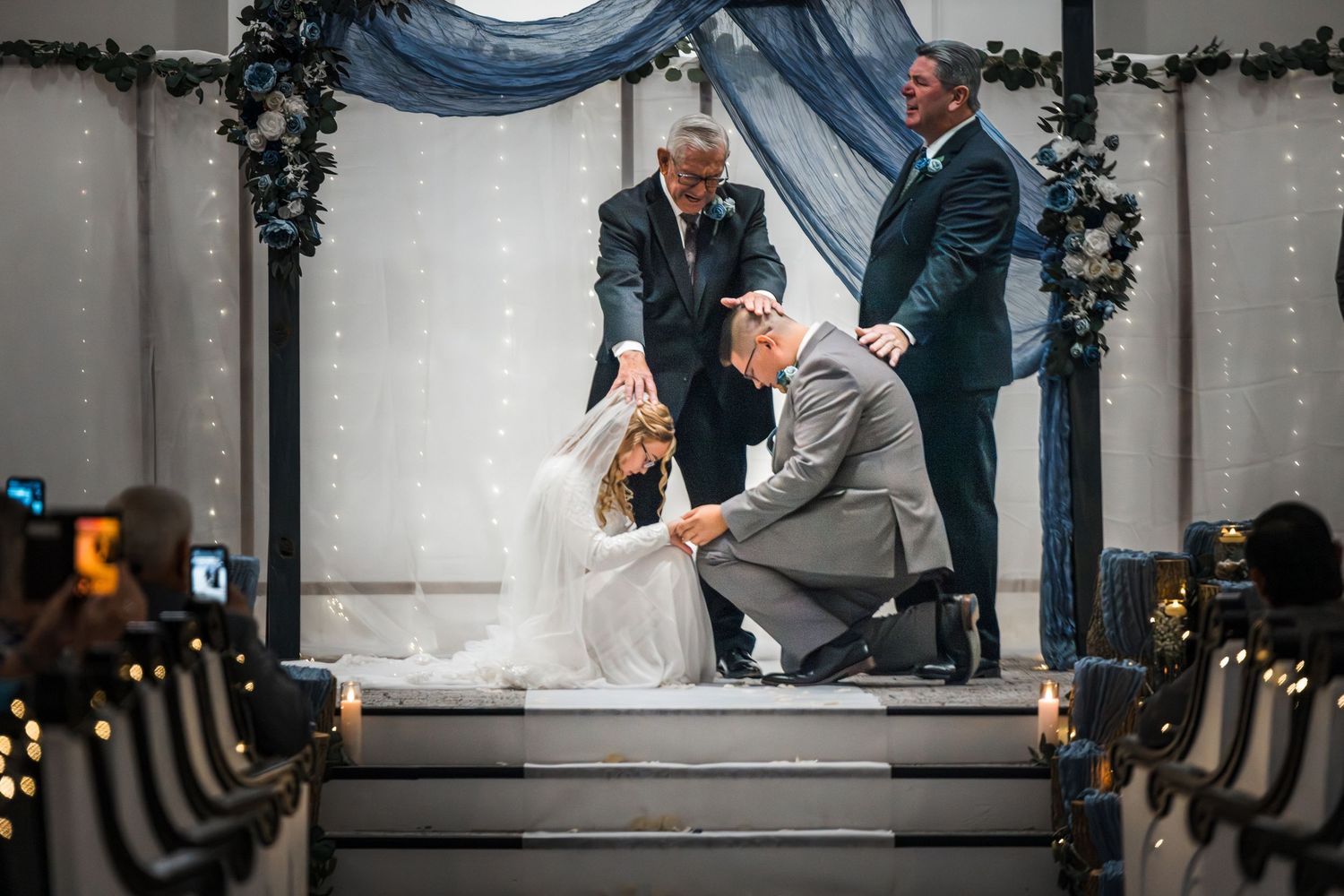 Wedding ceremony moments captured in an elegant indoor venue with decorative lighting and floral arrangements.