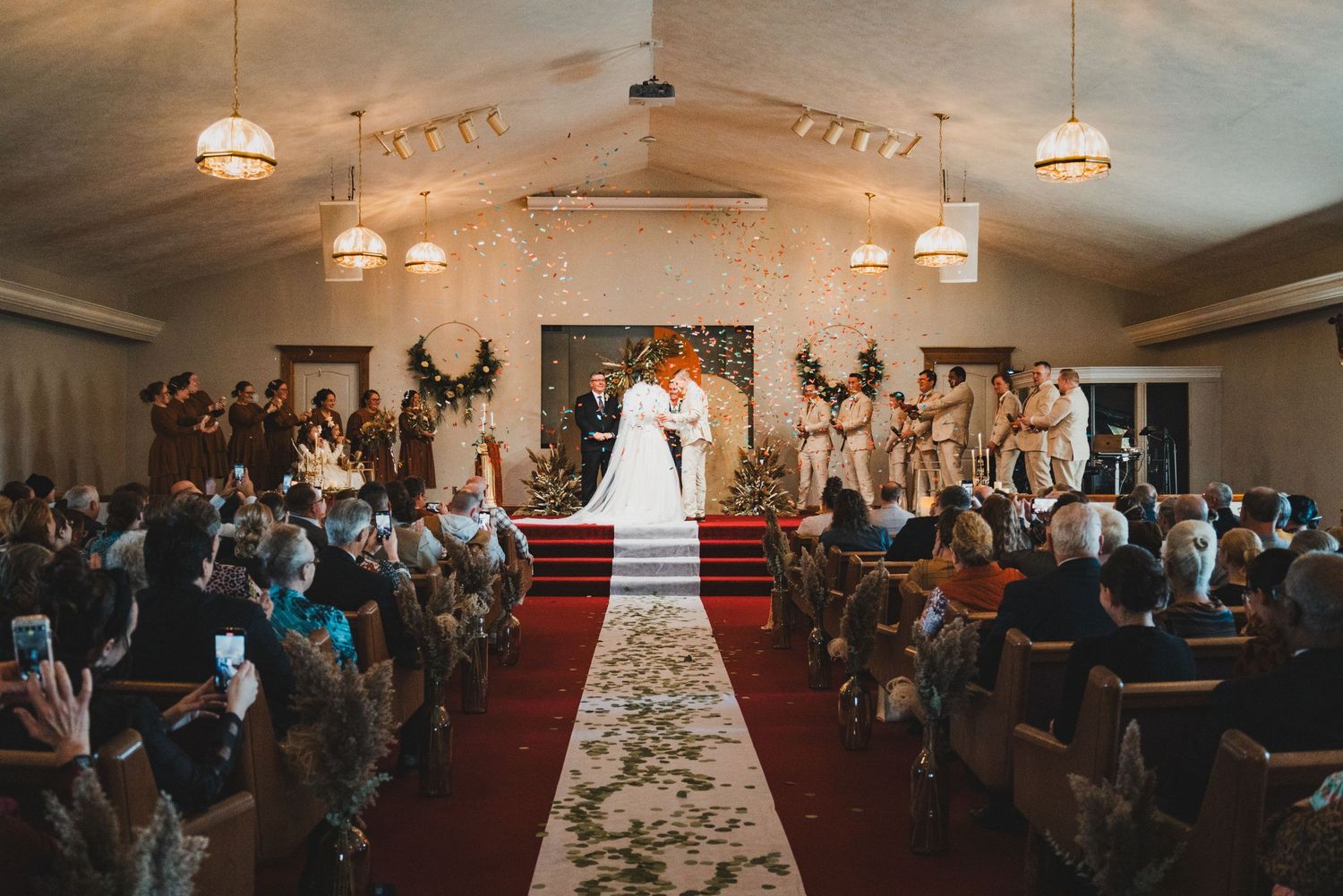 Wedding ceremony in progress inside decorated church venue with guests in attendance.