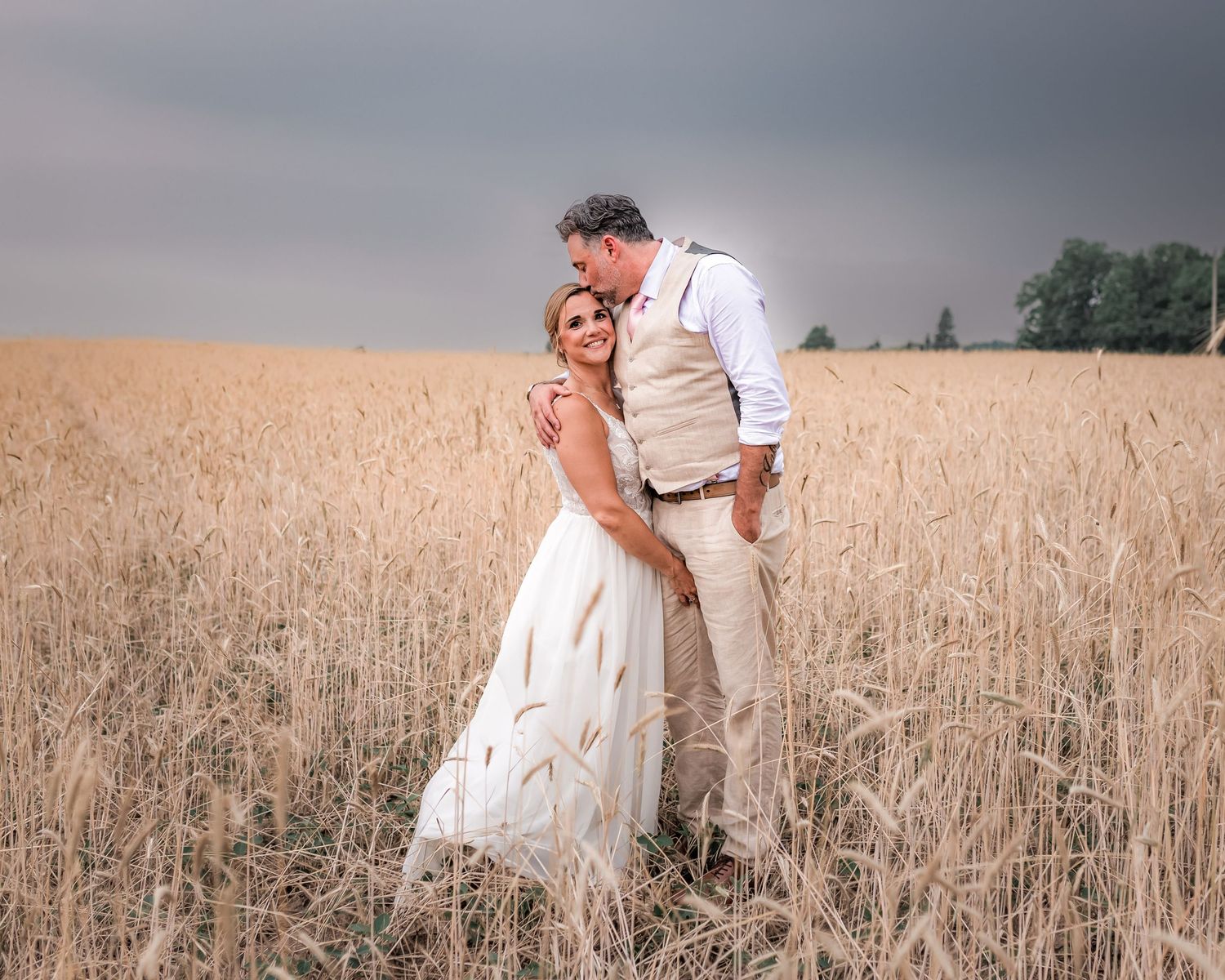 Romantic couple embracing in a golden wheat field during sunset.