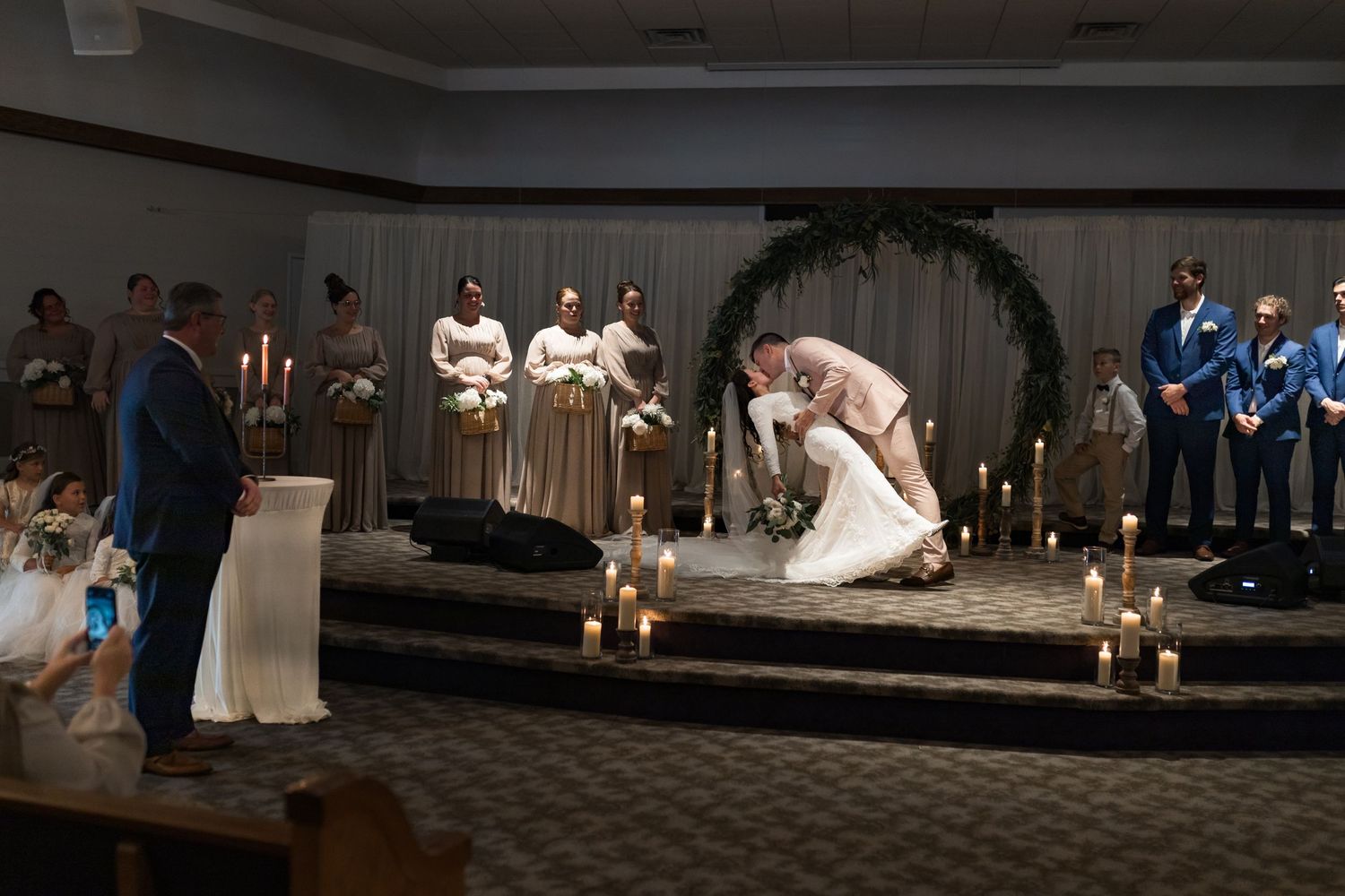 Indoor wedding venue decorated with candles and greenery for evening ceremony.