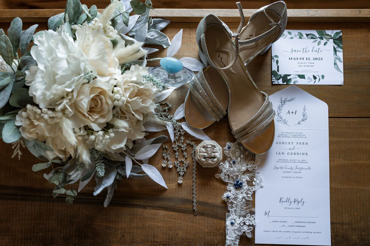 Wedding stationery and floral decorations artfully arranged on wooden surface.