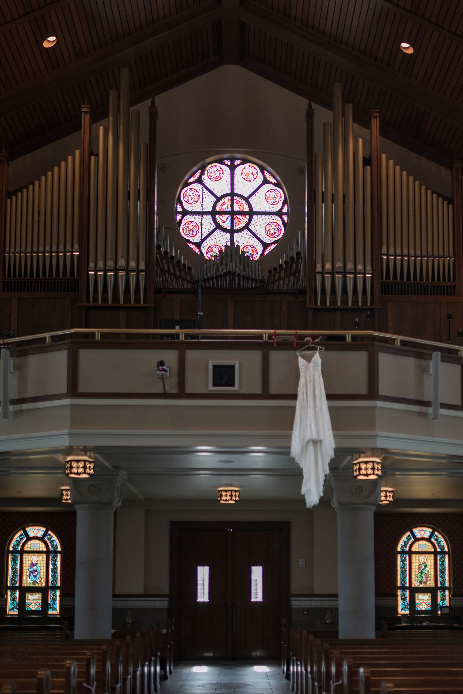 Interior of a church with stained glass windows and organ pipes visible in the balcony.