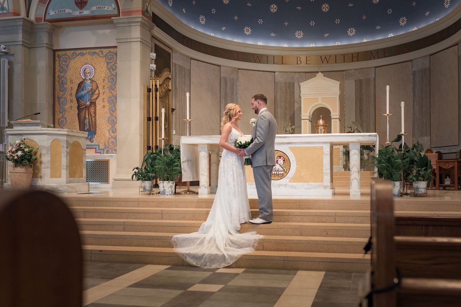Wedding ceremony in a grand church with ornate ceiling and traditional altar decorations.