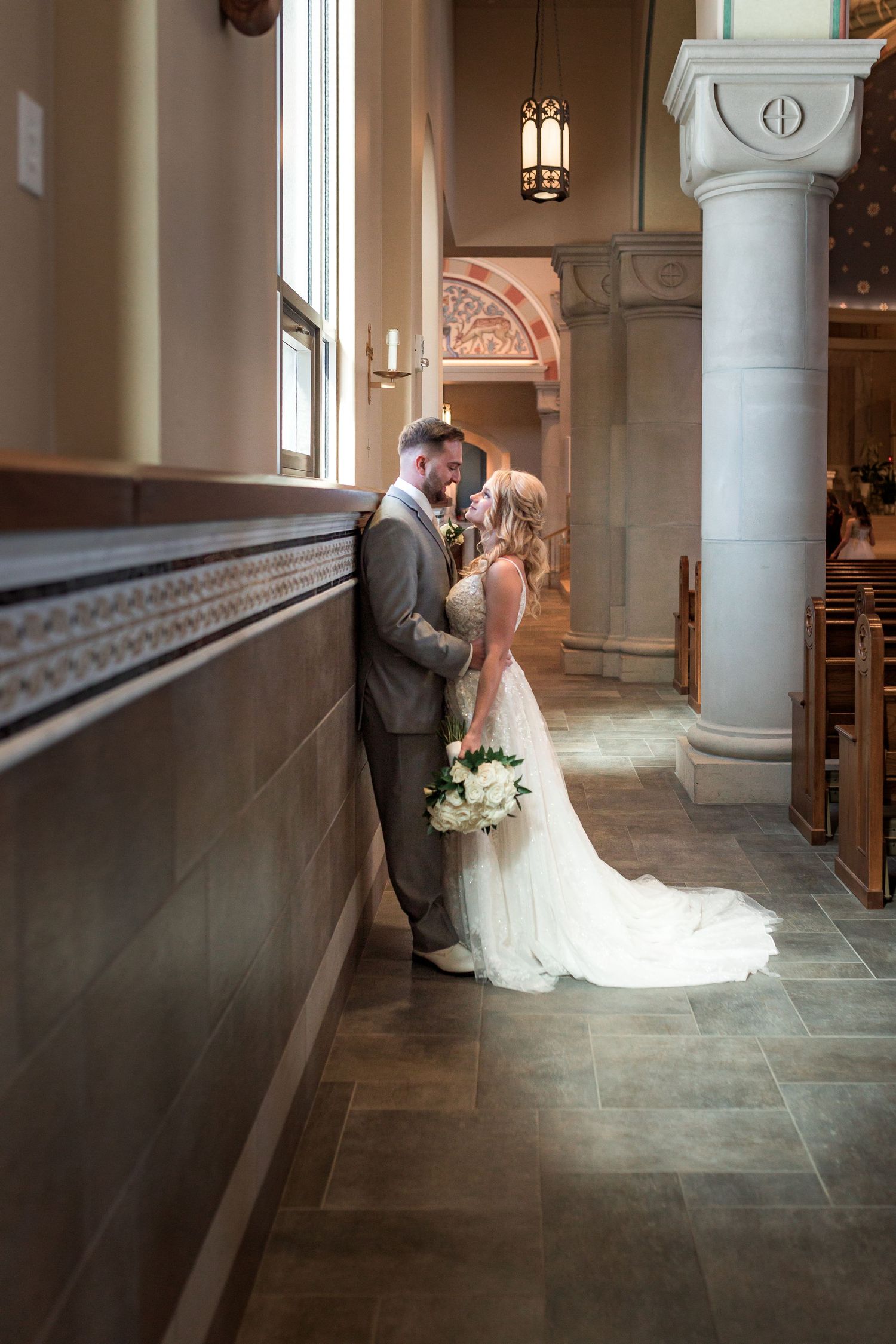 Intimate moment captured in a church aisle with natural light streaming through windows.
