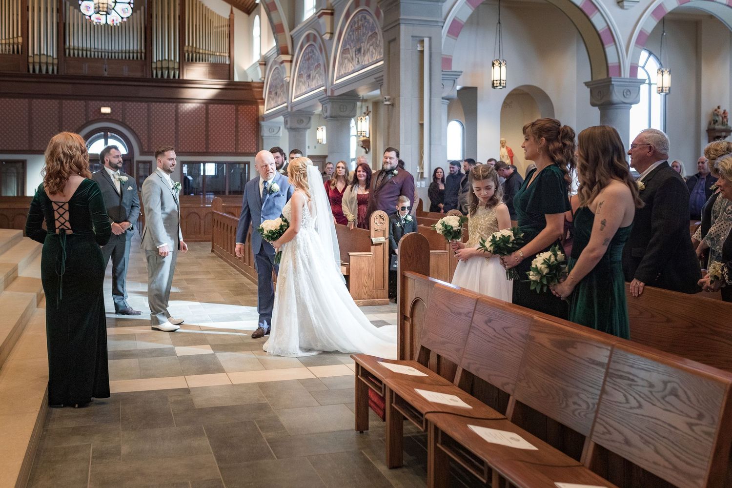 Wedding ceremony procession in a traditional church with wooden pews and vaulted ceilings.