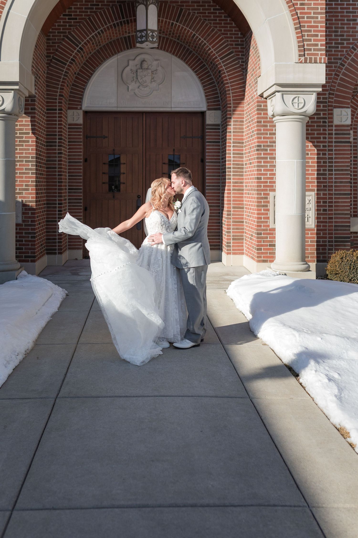 Elegant wedding moment captured under a brick archway entrance.