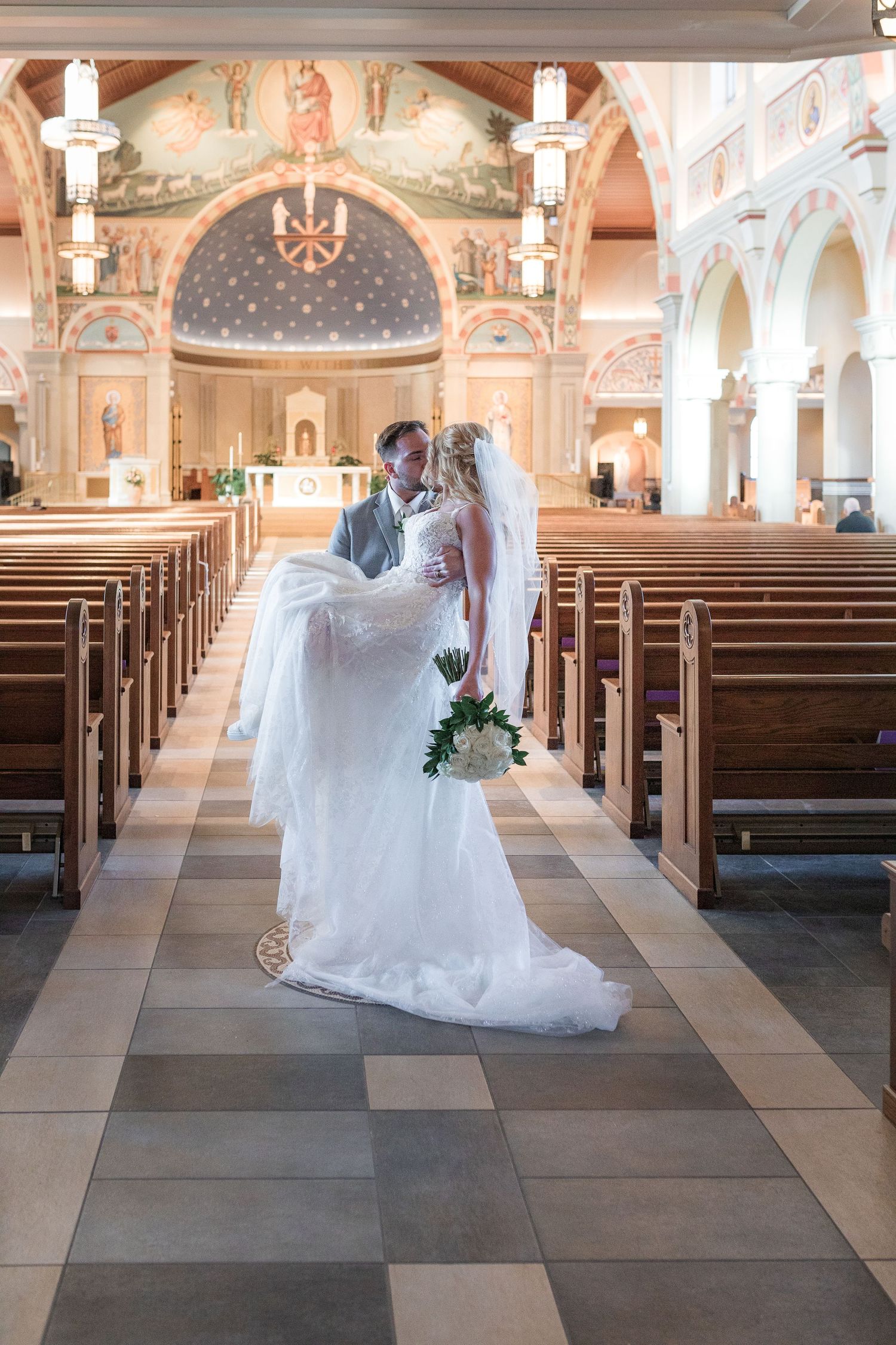 Wedding ceremony in a beautiful church with ornate murals and traditional wooden pews.