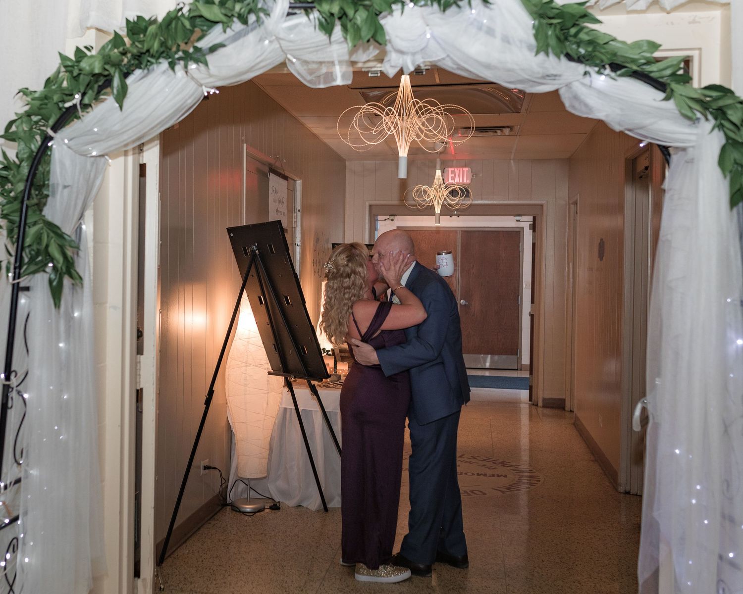 Wedding reception hallway decorated with white floral garlands and twinkling lights.