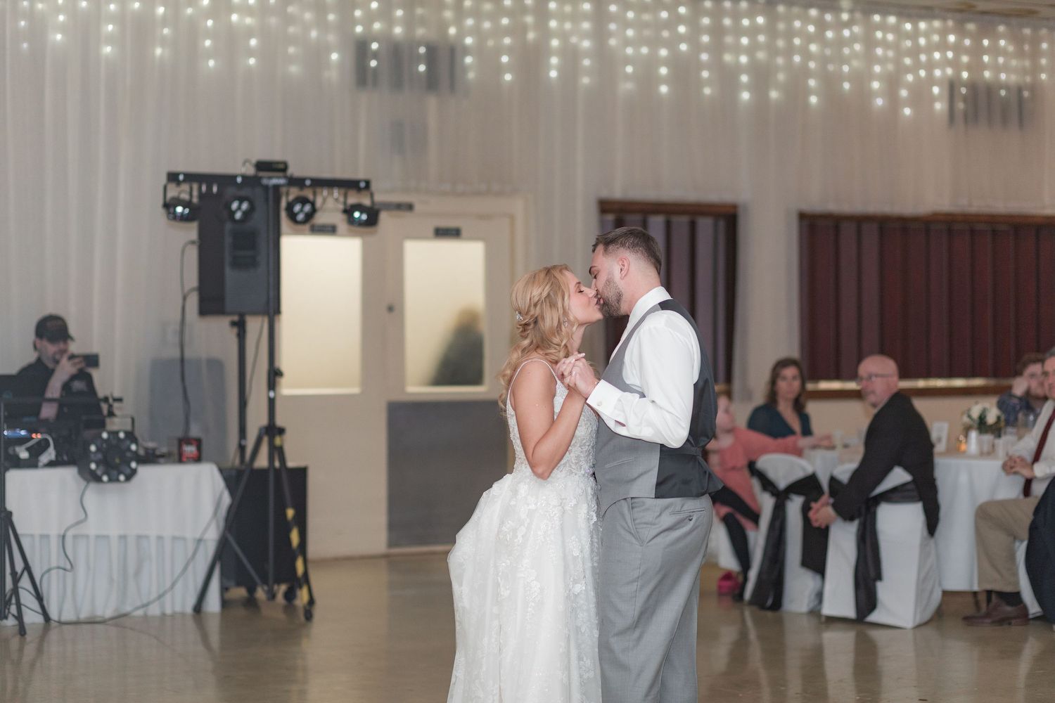Reception venue with romantic string light backdrop and elegant white decor.