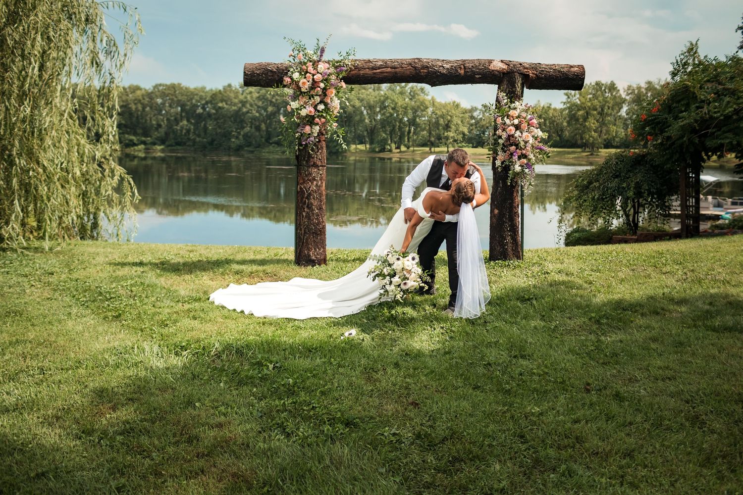 Beautiful outdoor wedding ceremony setup by a lake with natural landscape and floral decorations.