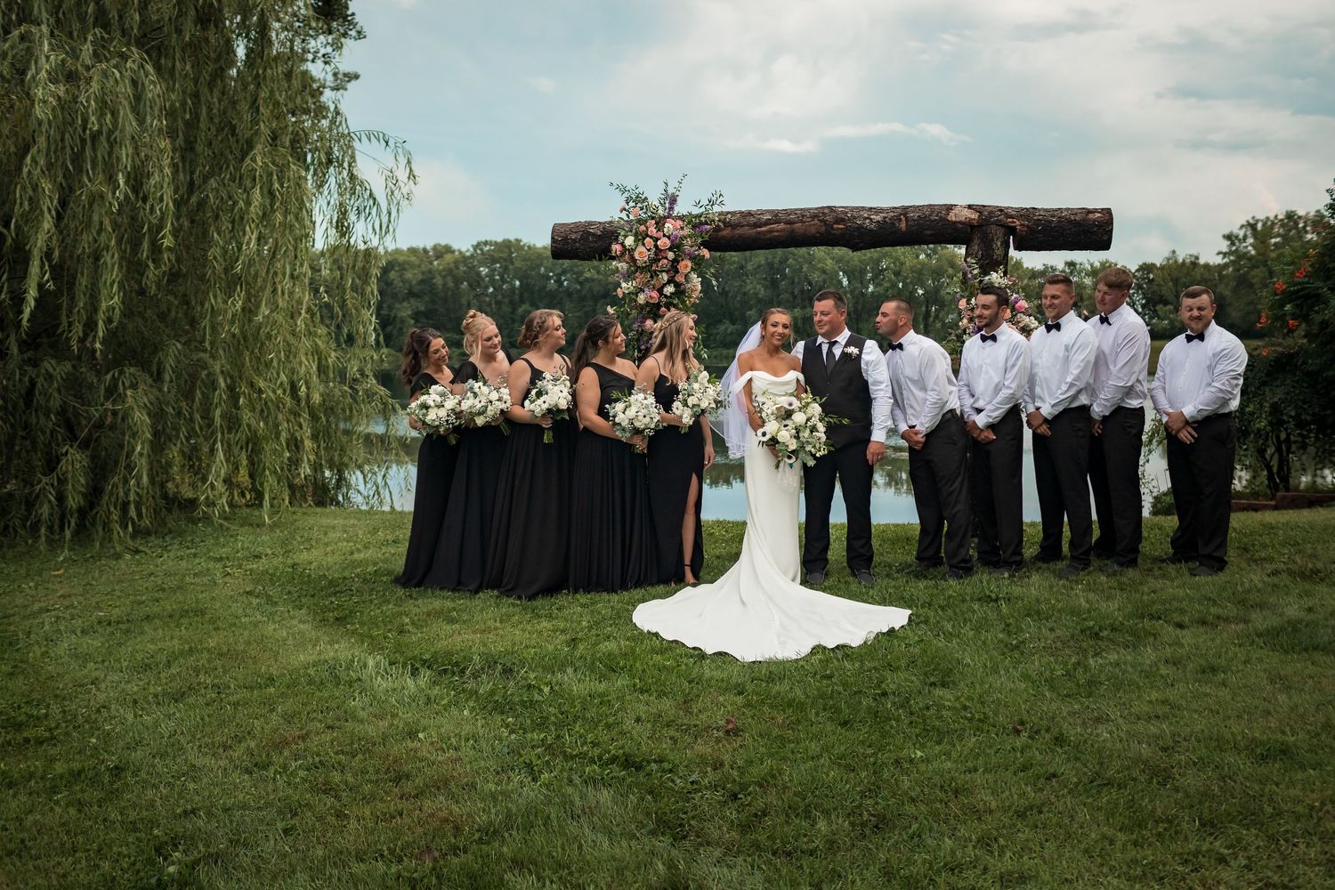 Panoramic view of a lakeside wedding ceremony with guests gathered under blue skies.