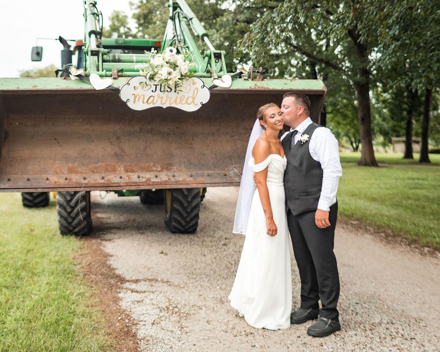 Wedding couple posing near rustic farm equipment and natural outdoor settings.