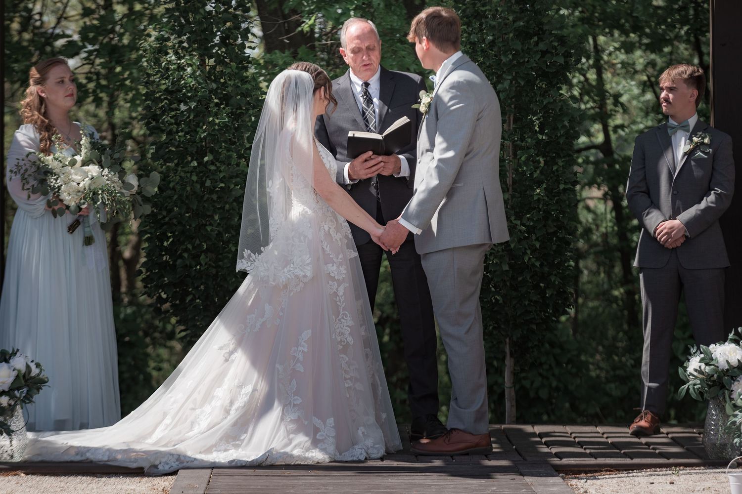 Outdoor wedding ceremony with couple exchanging vows under natural greenery.