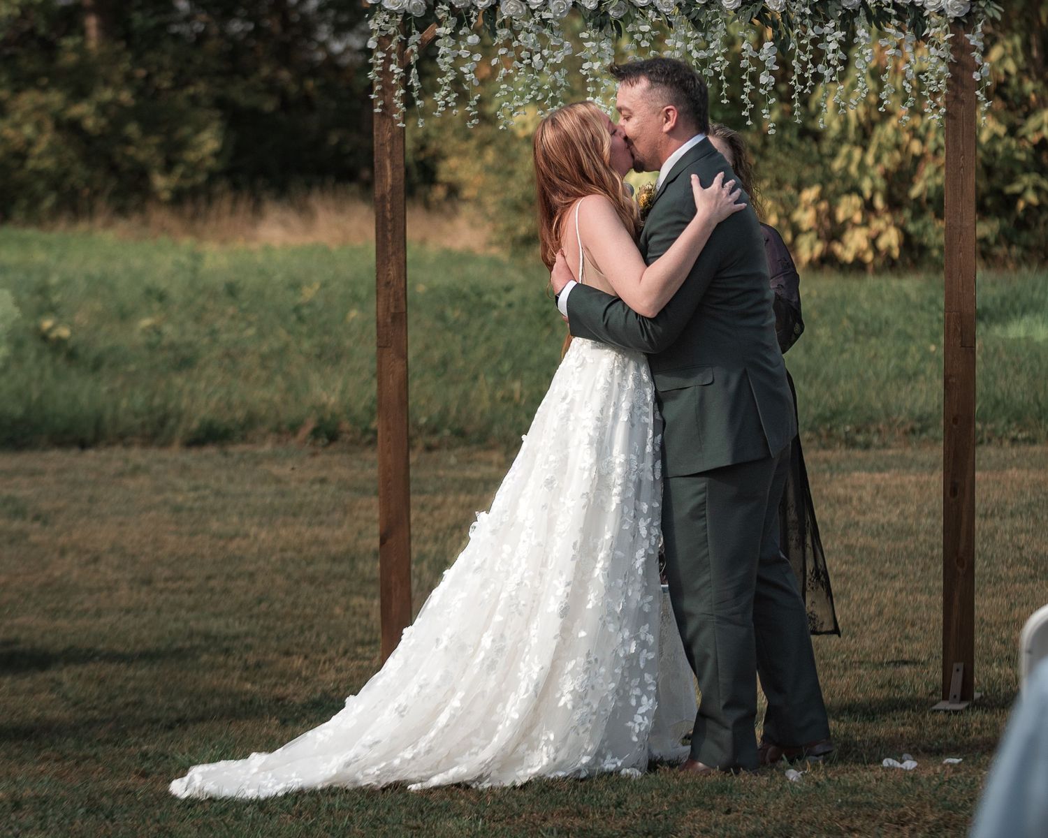 Wedding couple embraces under hanging lights at an outdoor venue during their celebration.