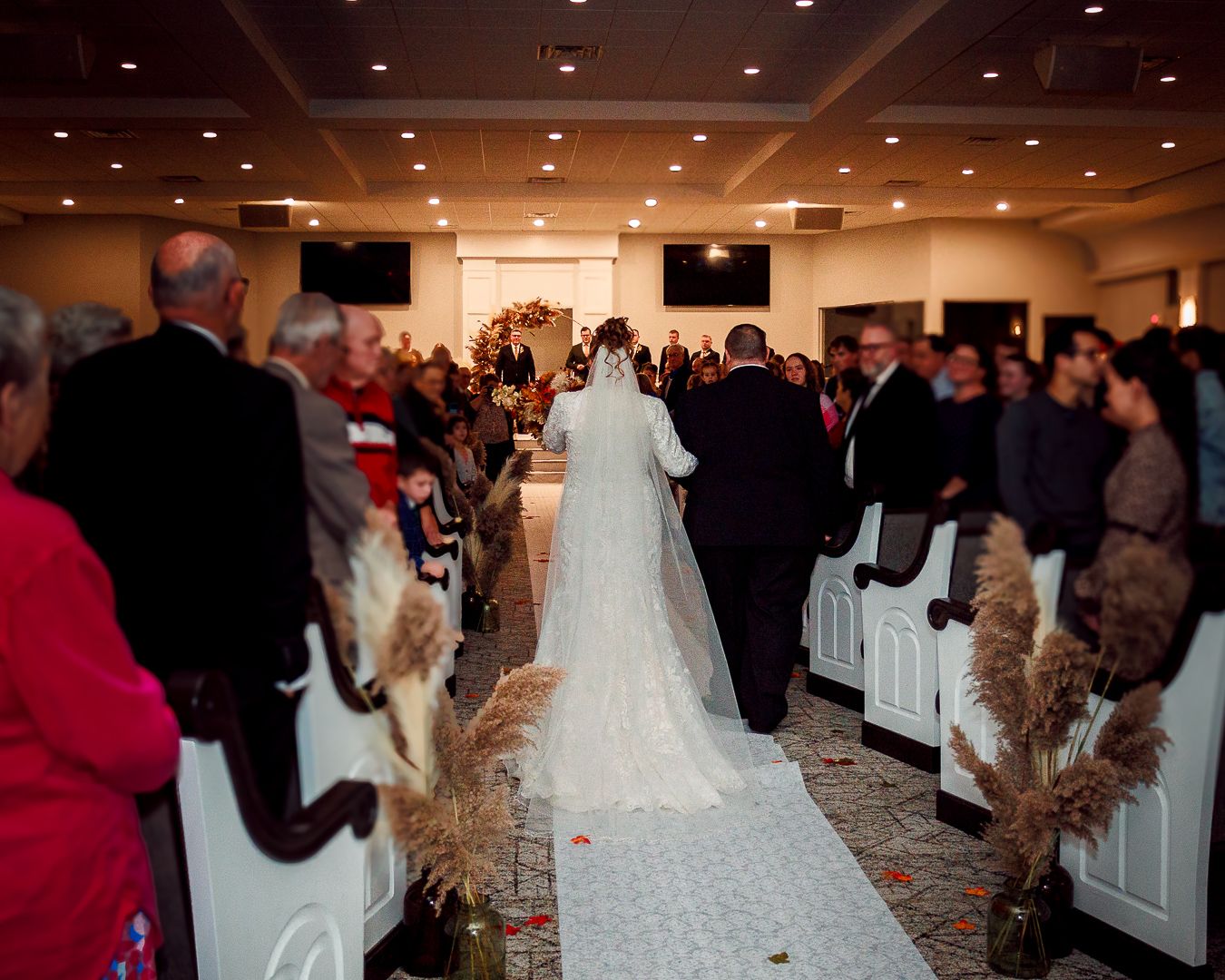 Wedding ceremony in progress with guests seated in large indoor venue.
