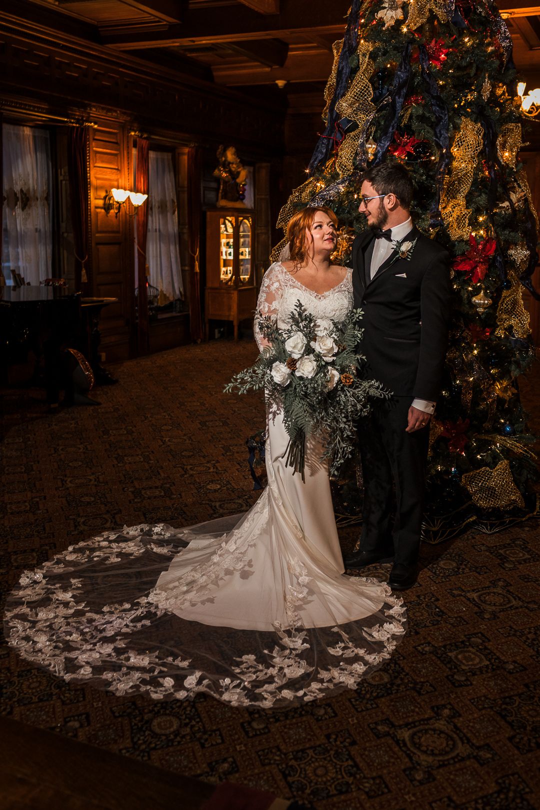 Romantic wedding portraits in a rustic wooden venue with Christmas decorations and twinkling lights.