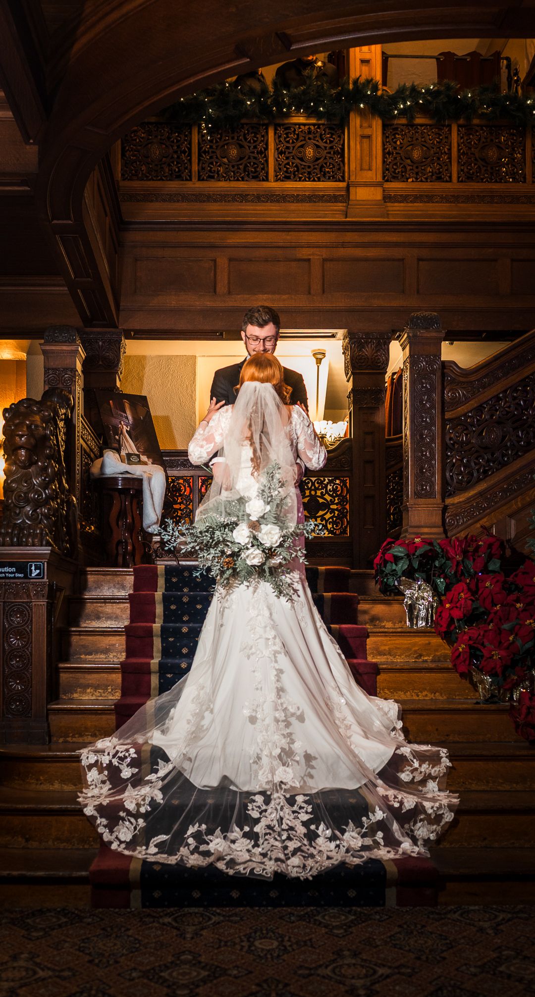 Elegant wedding dress with intricate lace details photographed in a warmly lit wooden interior.