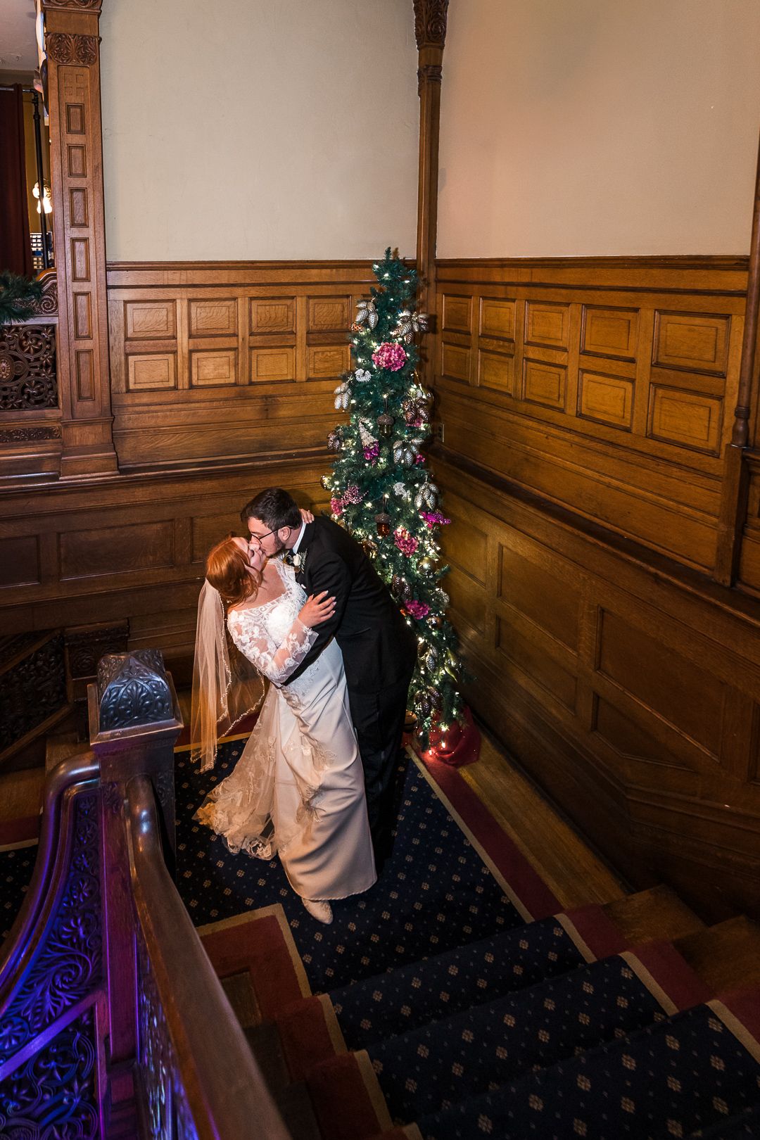 Intimate wedding moment captured in a historic church with wooden paneling and holiday decor.