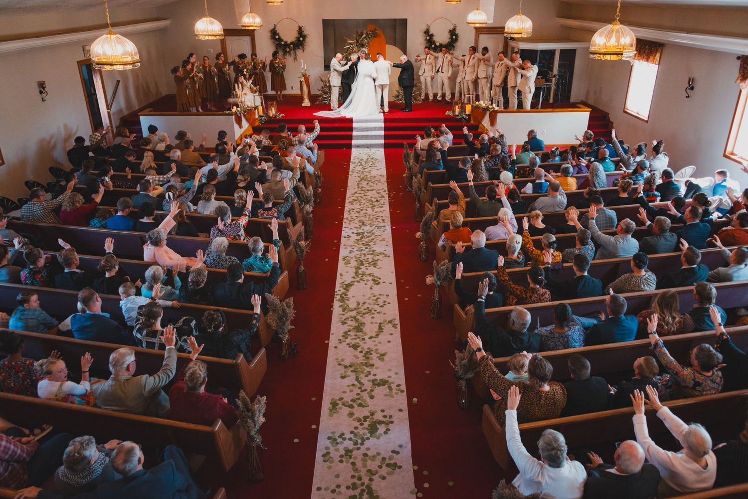 Wedding ceremony in traditional church with guests seated in wooden pews.