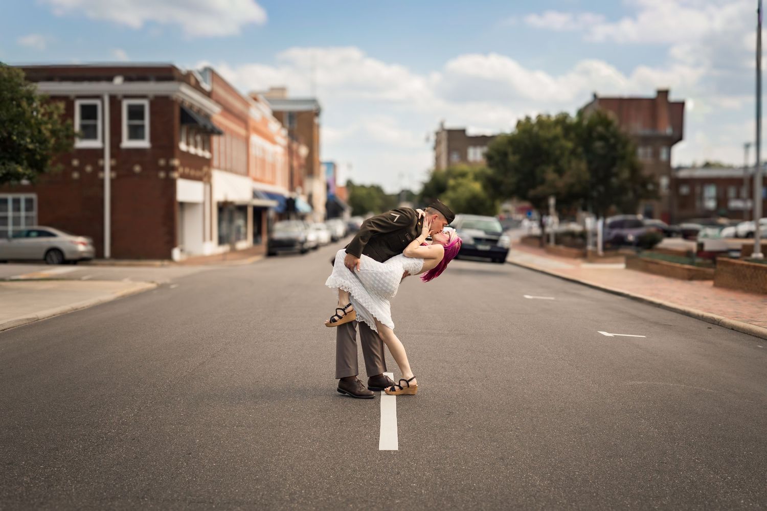 Couple sharing a romantic dip kiss in the middle of a small town street on their wedding day.