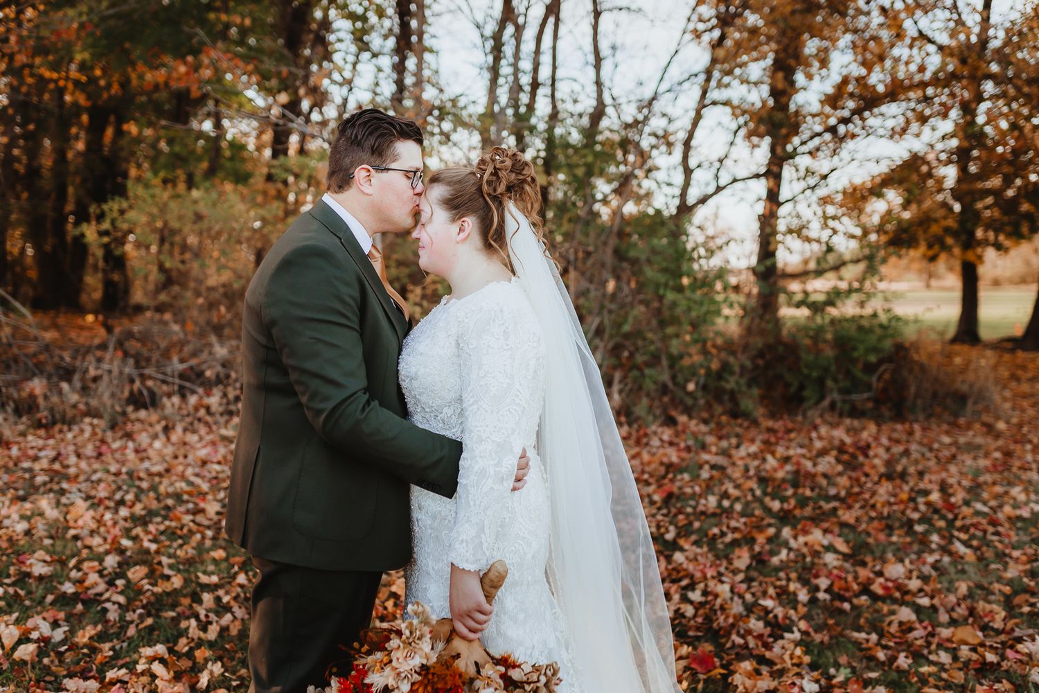 A romantic autumn wedding photoshoot with fallen leaves creating a warm rustic backdrop.
