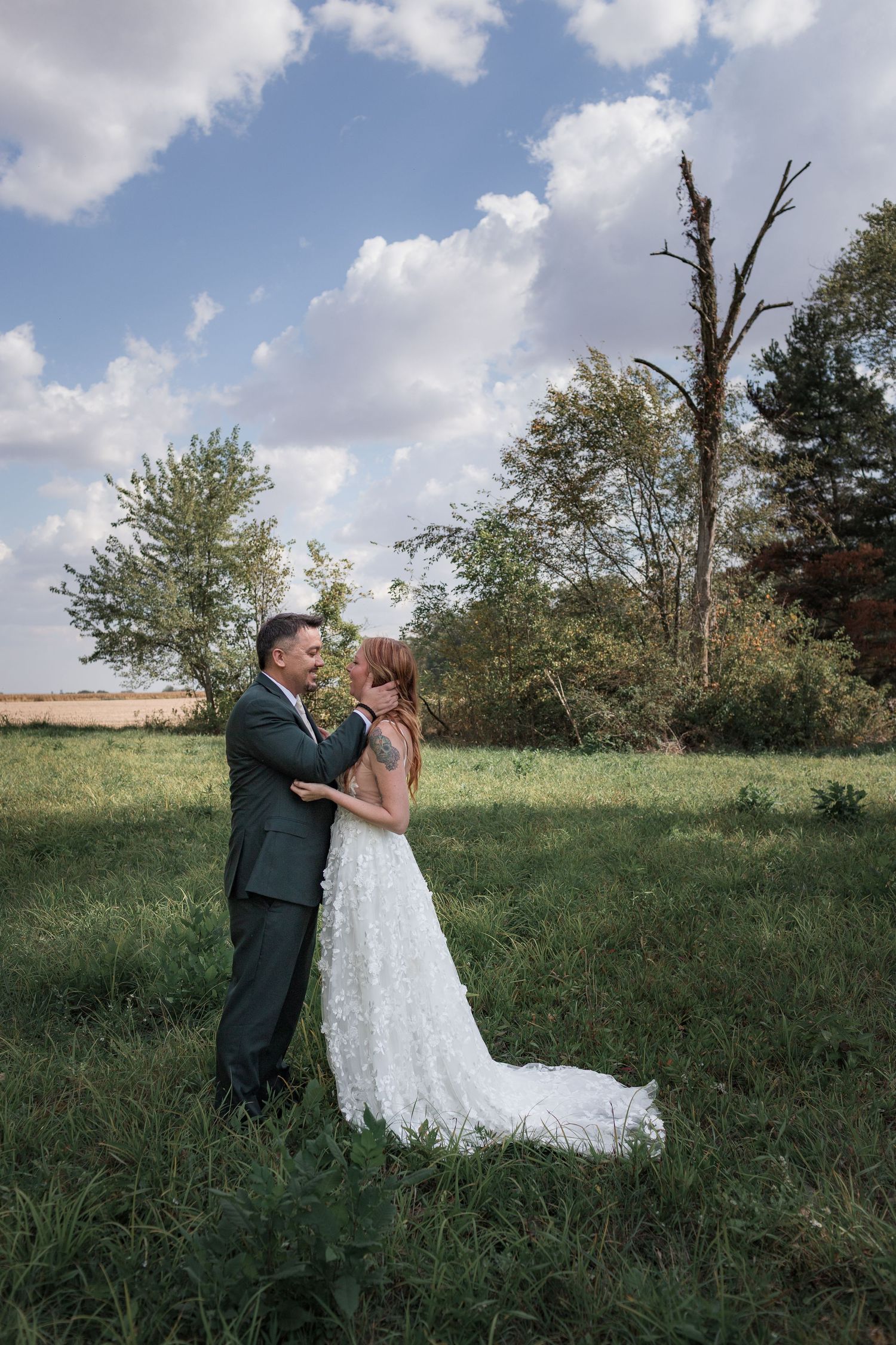 Outdoor wedding photography session in a rustic field with natural lighting and blue skies.