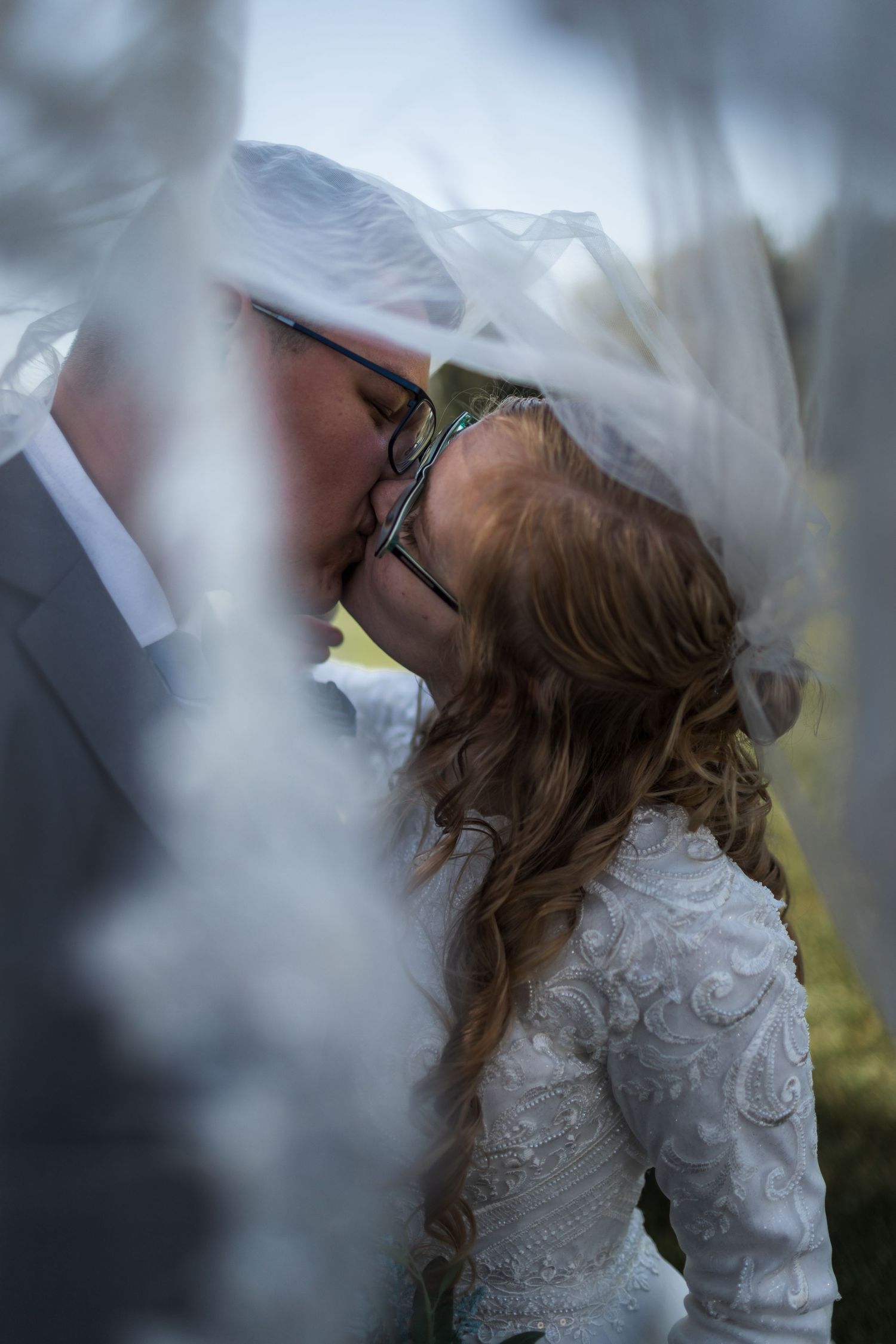 Wedding couple sharing a romantic moment under a flowing white veil.