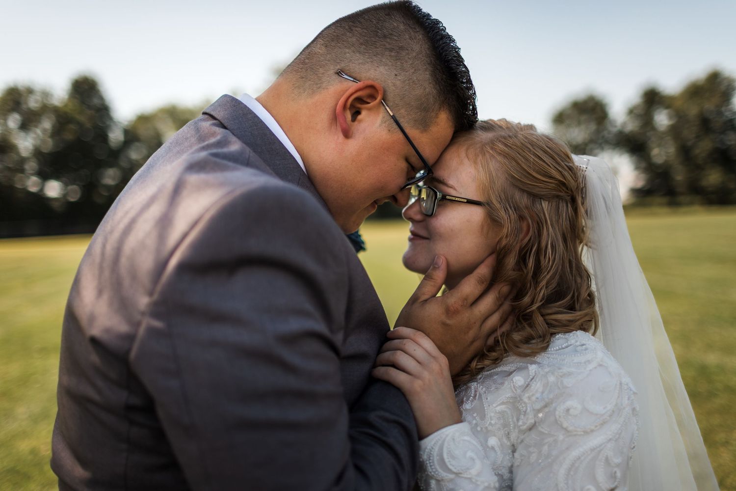 Intimate moment between newlyweds during outdoor wedding photoshoot.