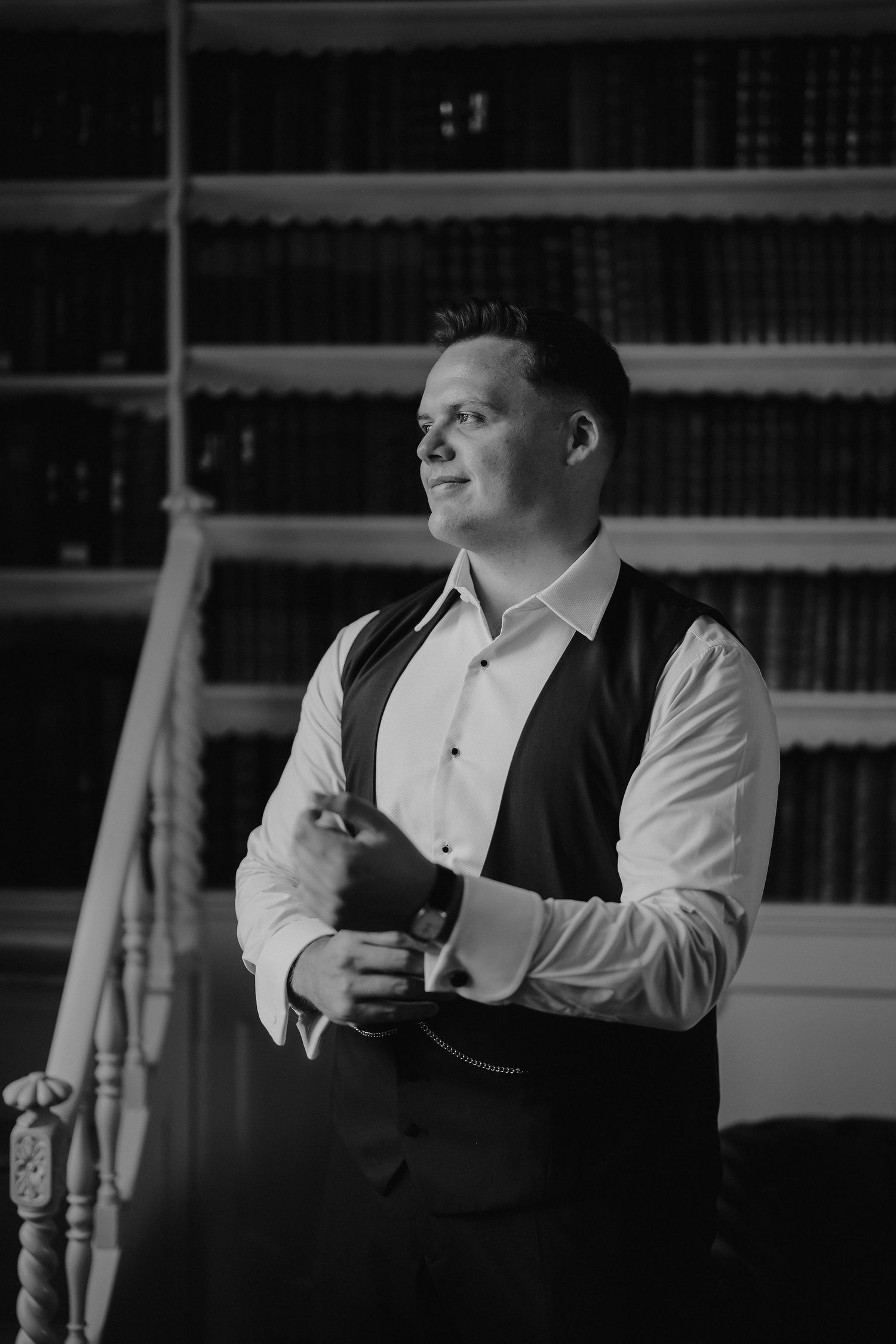 groom fastening cufflinks in the library at Iscoyd park