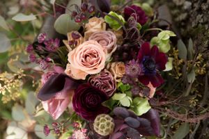 Luxurious wedding bouquet with pink roses, burgundy flowers and mixed greenery.