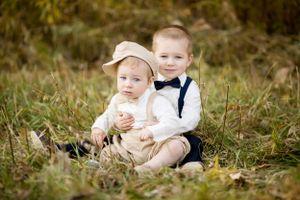 Young children in formal wear sitting together in autumn field.