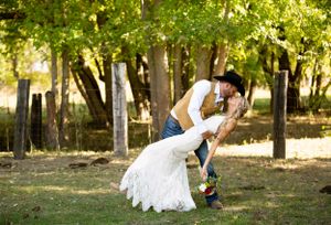 Romantic wedding dip pose captured in a sun-dappled forest setting.