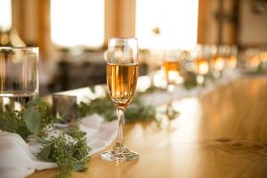 Champagne flute with golden liquid sits on decorated table with greenery garland.