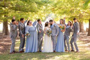 Wedding party poses playfully under pine trees in gray suits and powder blue dresses.