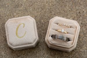Wedding rings displayed in a velvet ring box with gold monogram letter C.