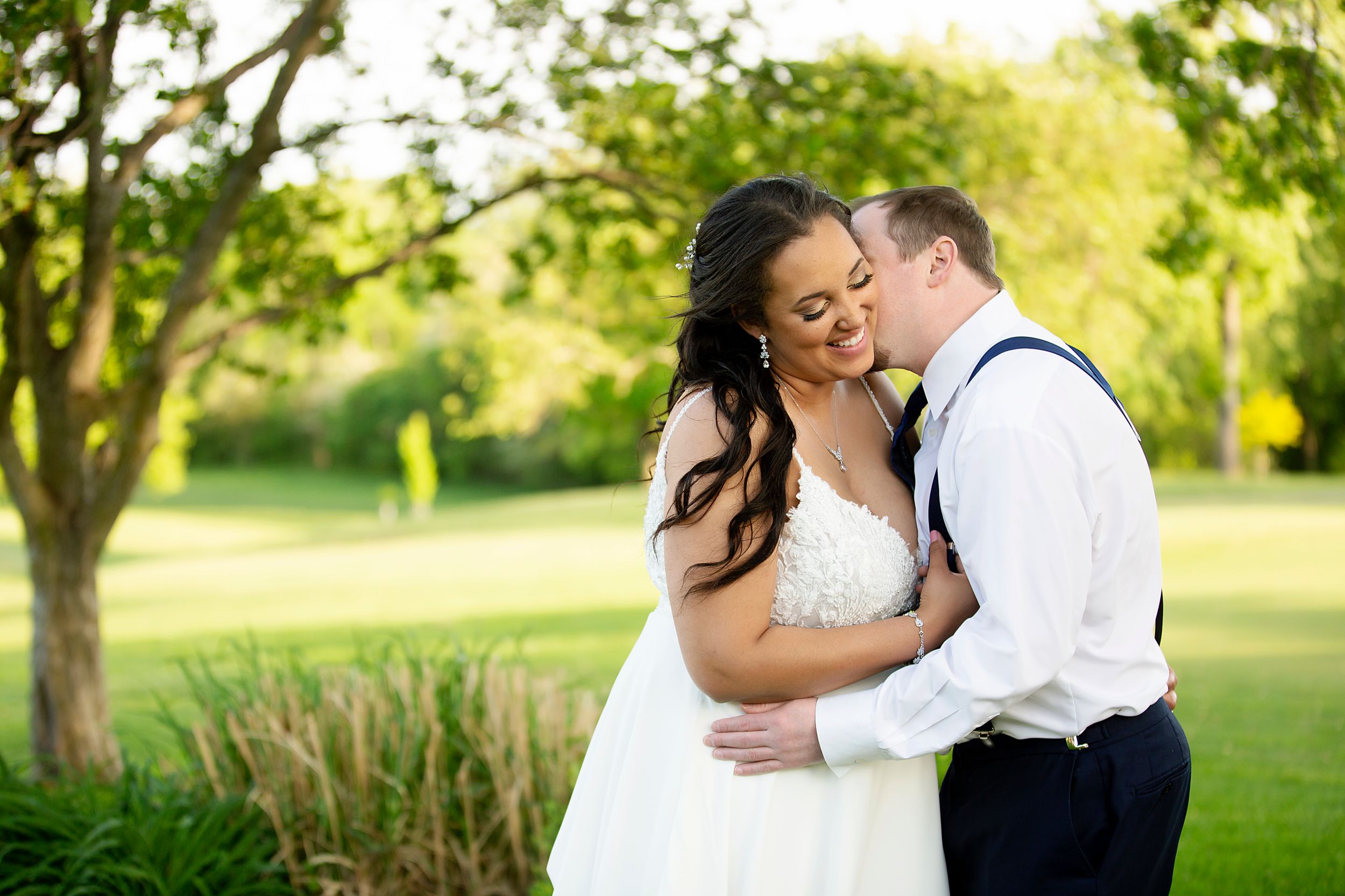 Intimate wedding portrait captured in lush garden setting during golden hour.
