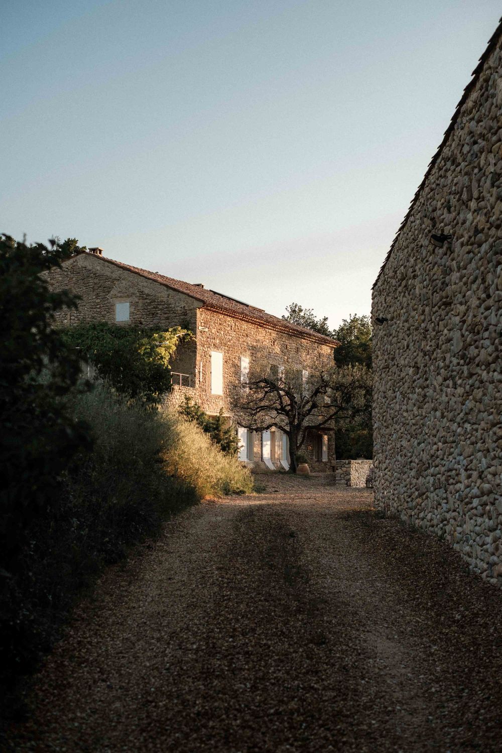 Stone pathway between rustic buildings in a traditional French village at dusk.