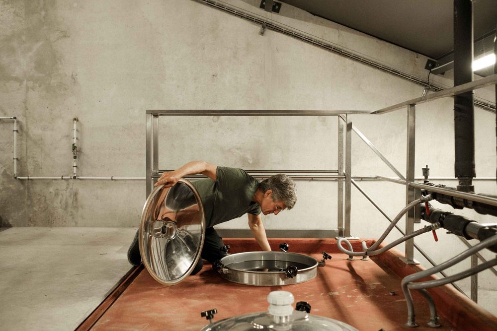 Someone working with equipment in an industrial winery cellar setting.