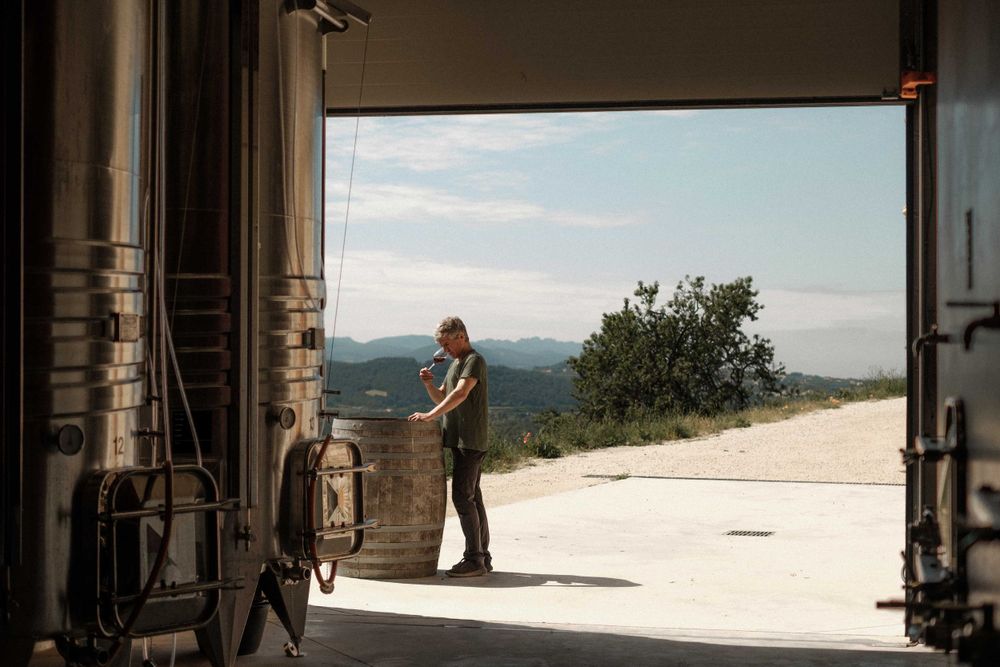 A scenic view through an open doorway showing someone standing at an outdoor viewpoint overlooking distant hills.