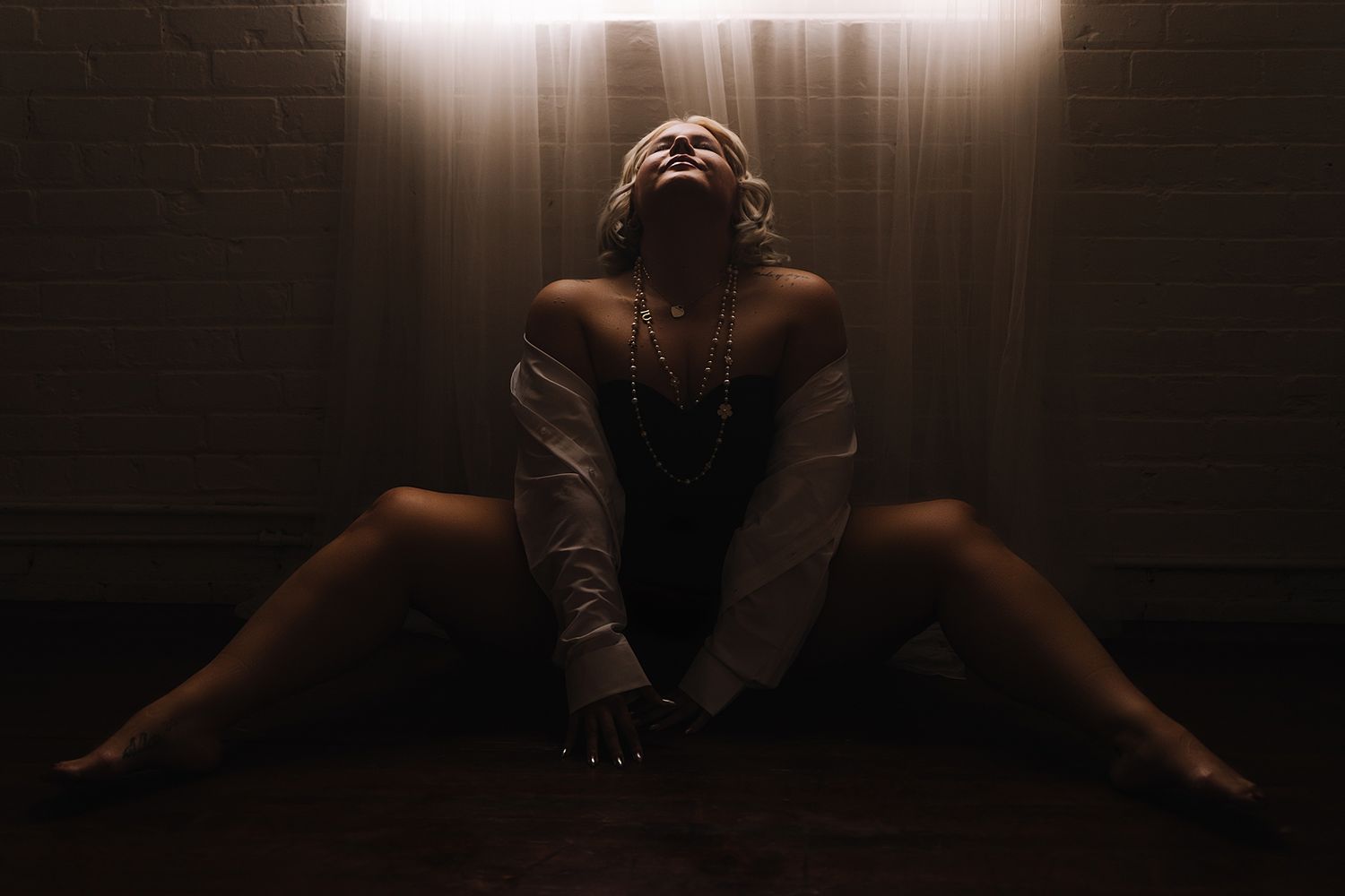 An artistic dark and moody boudoir portrait with dramatic lighting.
