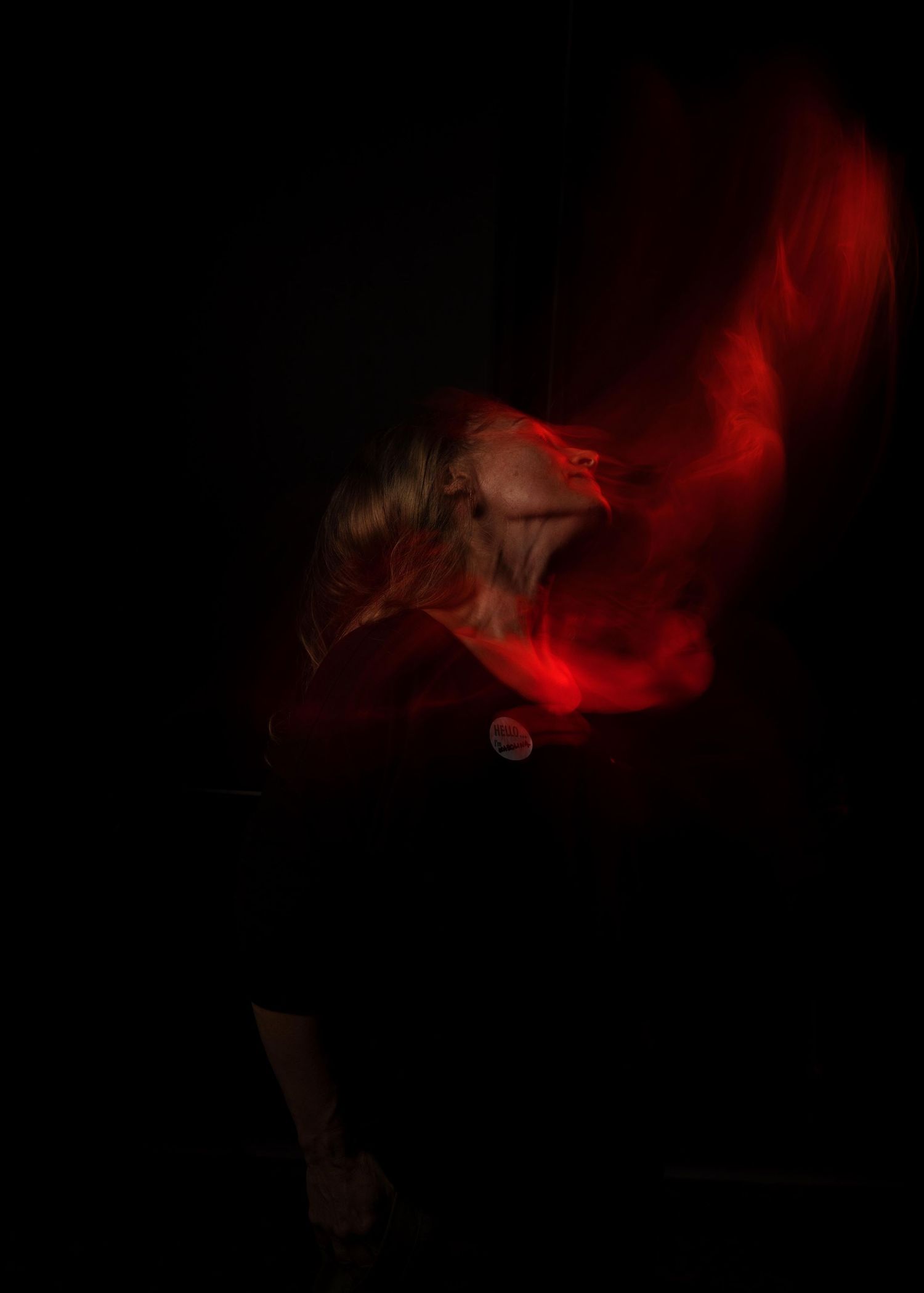 Silhouette figure in dramatic pose against dark background with swirling red smoke or fabric creating ethereal effect.
