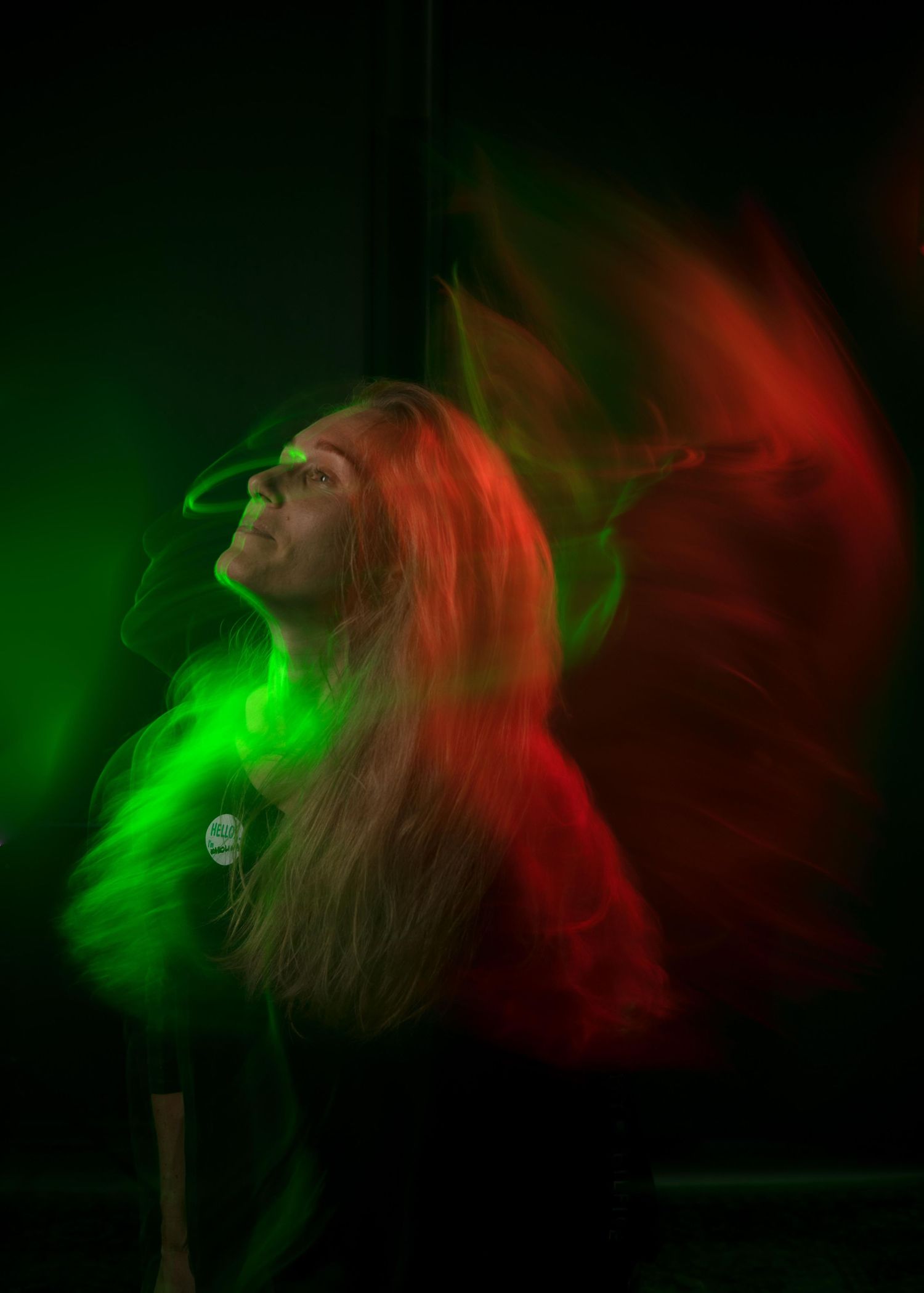 Silhouette surrounded by vibrant red and green stage lighting creating an ethereal atmospheric effect during performance.